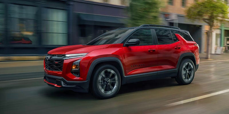 Red 2025 Chevrolet Equinox driving down road in city